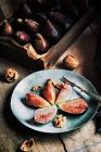 Свіжі інжири, подані на тарілці з горіхами на дерев'яному сільському столі — стокове фото