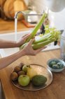 Female hands washing green vegetables and fruits in sink under stream of fresh water in kitchen — Stock Photo
