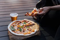 Nahaufnahme einer weiblichen Hand, die ein Stück Pizza nimmt — Stockfoto