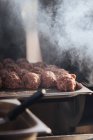 Balls of raw meat composed on metal tray for burger patties in smoke of grill — Stock Photo