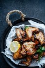 Close-up of baking dish of baked chicken wings in sesame and parsley with lemon — Stock Photo
