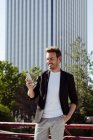 Элегантный парень с помощью смартфона, опираясь на перила на улице современного города — стоковое фото