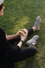 Stilvolle Frau sitzt auf Gras im Park und hält leckeren Burger zum Mitnehmen — Stockfoto