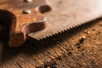 Close-up of old rusty handsaw on wooden surface — Stock Photo