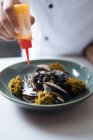 Chef pingando com molho prato de frutos do mar nórdicos com mexilhões no prato — Fotografia de Stock