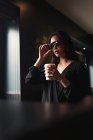 Mulher morena em óculos de sol segurando xícara de papel de café — Fotografia de Stock