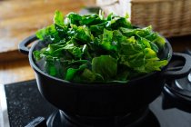 Spinach leaves in pot on gas stove — Stock Photo