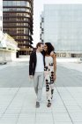 Cheerful multiracial couple hugging while walking on city street together — Stock Photo