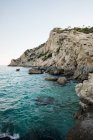 Onde turchesi sotto scogliere rocciose di costa tropicale sul mare contro il cielo blu . — Foto stock