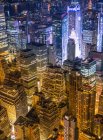 Magnifica vista aerea di alti edifici moderni in vetro e cemento in metropoli illuminati da luci luminose di notte — Foto stock