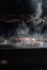 Raw burger patties roasting on grid of barbecue grill outdoors — Stock Photo