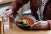 Mann isst traditionelle nordische rote Suppe garniert mit Kräutern — Stockfoto