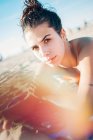 Красива молода дівчина лежить на пляжі на сонячному світлі і дивиться на камеру — стокове фото