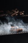 Raw burger patties roasting on grid of barbecue grill outdoors — Stock Photo