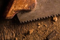 Gros plan de la vieille scie à main rouillée sur la surface en bois — Photo de stock