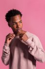 Hipster schwarzer Mann posiert auf rosa Hintergrund und schaut weg — Stockfoto
