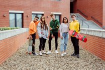 Groupe multiethnique d'adolescents en vêtements décontractés avec planches à roulettes debout sur la rue et regardant la caméra — Photo de stock