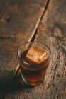 Ice cold brew coffee in glass on wooden surface — Stock Photo