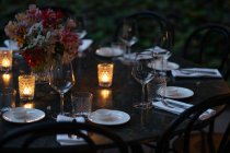 Mesa de ajuste decorada com velas e flores à noite — Fotografia de Stock
