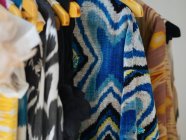 Coloridos vestidos indígenas diferentes cuelgan de perchas de madera - foto de stock