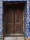 Exterior shot of aged wood carved door with amazing decor of blue tiles around, Uzbekistan — Stock Photo