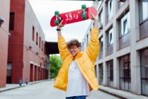 Adolescente com skate em pé na rua — Fotografia de Stock