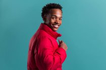 Trendy smiling man in red puffy jacket on blue background looking at camera — Stock Photo