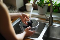 Human hands washing grapes under sink tap in kitchen — Stock Photo