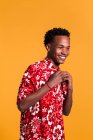 Stylish cheerful man in beach shirt on orange background — Stock Photo