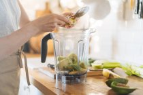 Frauenhände legen Früchte in Mixer-Schüssel für grünen Smoothie — Stockfoto