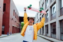 Adolescent avec planche à roulettes debout sur la rue — Photo de stock
