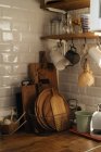 Интерьер кухни с белыми черепичными стенами и большим количеством посуды и приборов, составленных на полках и столешнице — стоковое фото