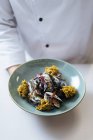Koch hält nordische Meeresfrüchte mit Miesmuscheln und Sahnesoße auf Teller — Stockfoto