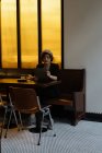 Jovem mulher bonita em boné sentado sozinho à mesa no restaurante moderno e ler através do menu — Fotografia de Stock