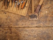 From above shot of shabby wooden table with set of craft tools for carving on wood, Uzbekistan — Stock Photo