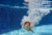 Child swimming in blue pool underwater with air bubbles — Stock Photo