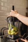 Female hands preparing healthy green smoothie with blender — Stock Photo
