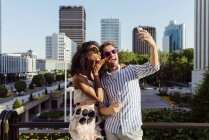 Fröhliches multiethnisches Paar posiert vor dem Hintergrund der modernen Stadt für ein Selfie — Stockfoto