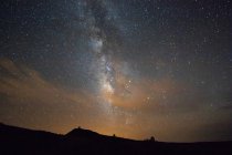 Starry sky with endless galaxy above dark terrain — Stock Photo