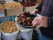 Personne tenant un bol en métal de figues séchées au marché fermier — Photo de stock