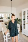 Porträt einer jungen Frau im karierten Hemd, die zu Hause am Küchentisch lehnt — Stockfoto