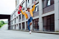 Glücklicher und aufgeregter Teenager springt mit Skateboard — Stockfoto