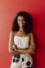 Портрет улыбающейся афроамериканки, стоящей на красном фоне — стоковое фото