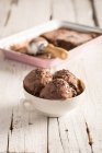 Balls of homemade chocolate ice cream in bowl on wooden surface — Stock Photo