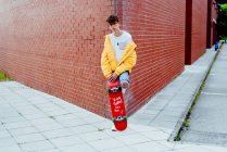 Підліток зі скейтбордом на розі — стокове фото