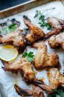 Baking tray with parchment and baked chicken wings in sesame and parsley with lemon — Stock Photo