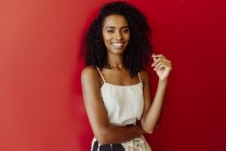 Портрет смеющейся афроамериканки, стоящей на красном фоне — стоковое фото