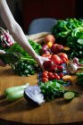 Vista de la cosecha de manos femeninas tomando potherbs de mesa elegante con verduras frescas y saludables ingredientes de cocina de frutas desde arriba - foto de stock