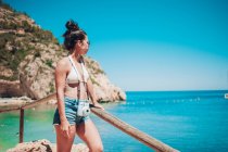 Jovem menina em roupas de verão inclinando-se sobre corrimão de madeira na praia — Fotografia de Stock