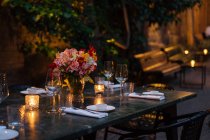 Встановлення столу, прикрашеного свічками та квітами вночі на задньому дворі — стокове фото
